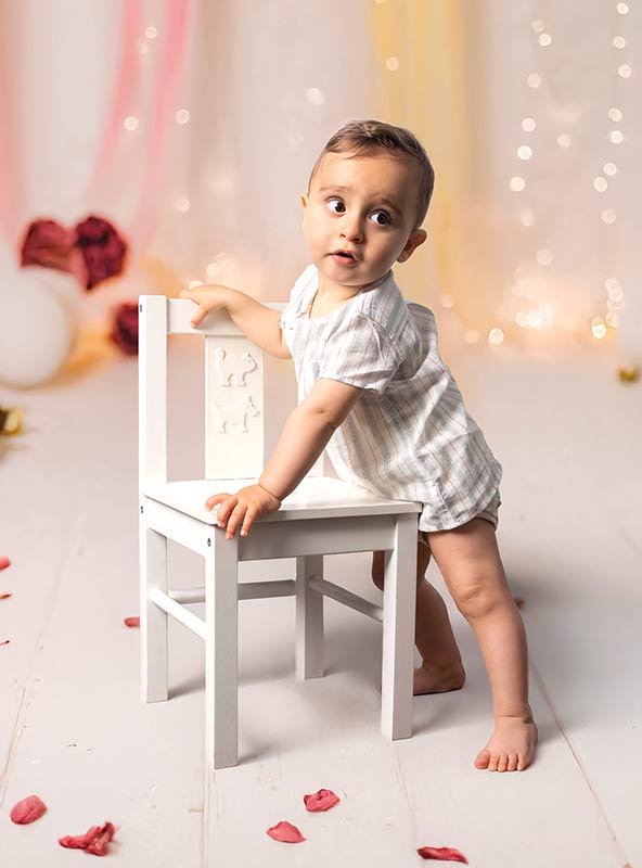 Primeros pasos del bebé de 12 meses. Fotografía infantil capturando el logro de ponerse de pie