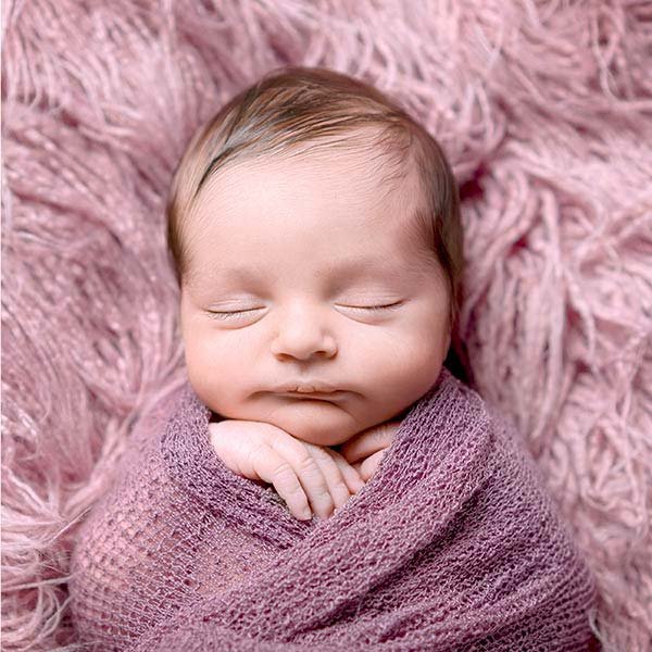 Bebé newborn durmiendo sereno con envoltura