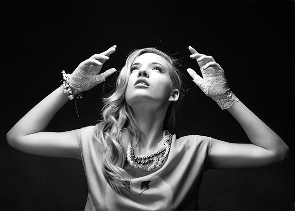 Retrato de estudio de chica gesticulando con las manos levantadas, enfocada en la luz superior